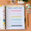 Open planner with colorful tabs on a desk with stationery items