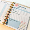 Open planner with book journal page and colorful binder rings.