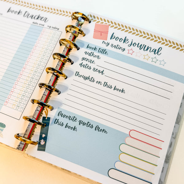 Open planner with book journal page and colorful binder rings.