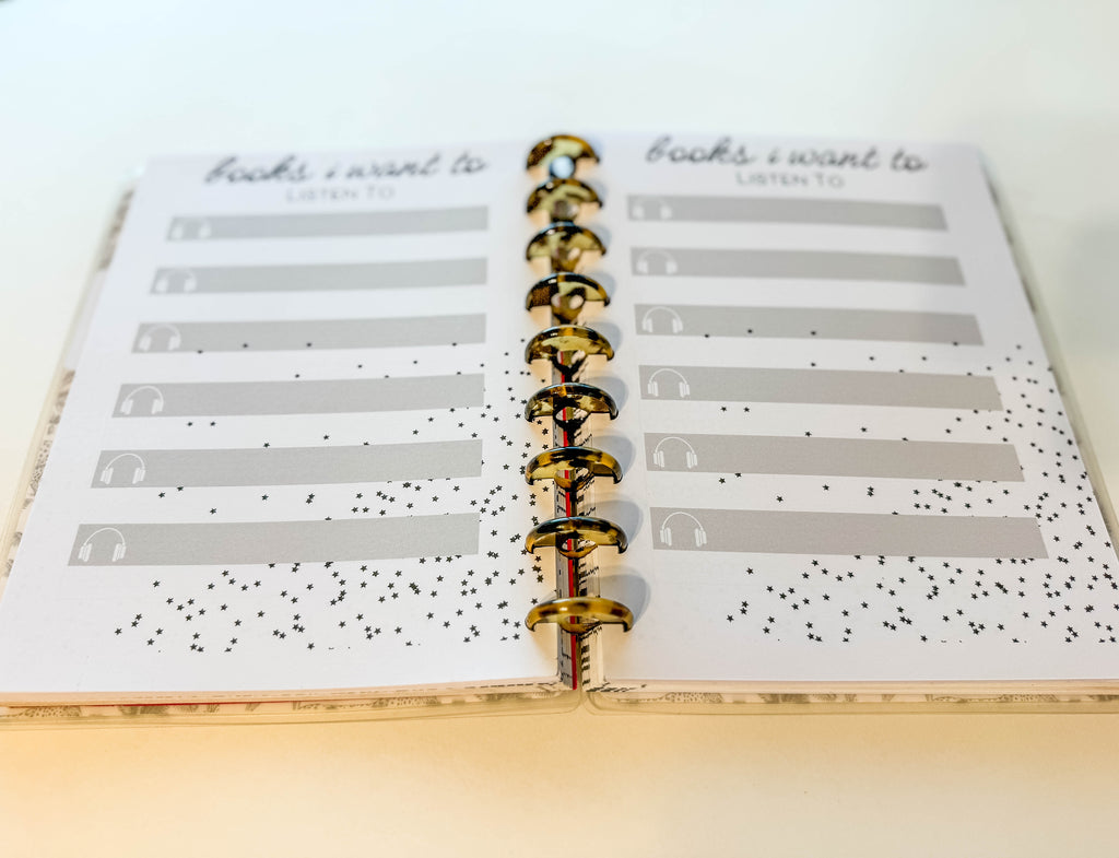 Open planner with a page titled 'books I Want to Listen To' on a light wooden surface.